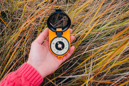 Woman traveler sitting on autumn nature background, point of view shot. Unrecognizable young girl on a hike in autumn forest with a compass in hand. Relax in a nature. Traveler resting in the natureの写真素材