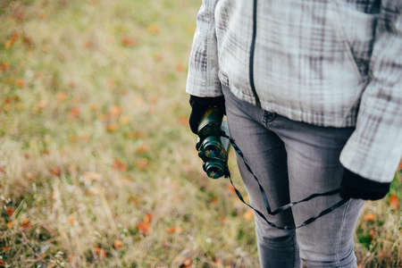 Young woman looking through binoculars on a autumn nature. Binocular, traveler, hiking.  young caucasian female hiker holding in his hand binoculars. Horizontal shape, front view,の写真素材
