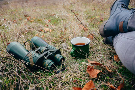 Young woman drinking tea on a autumn nature. Binocular, traveler, hiking.  young caucasian female...