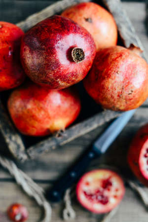 Ripe pomegranate fruit on wooden vintage background. Red juice pomegranate on dark background.  Fresh juicy pomegranate - whole and cut, top view.  Juicy pomegranates on woodの写真素材