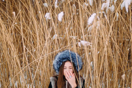 Young attractive girl embracing the snow in winter. Winter portrait of young womanの写真素材