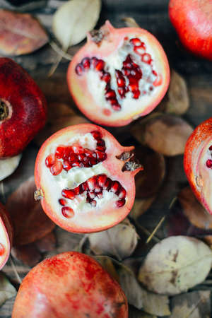 Ripe pomegranate fruit on wooden vintage background. Red juice pomegranate on dark background.  Fresh juicy pomegranate - whole and cut, top view.  Juicy pomegranates on woodの写真素材