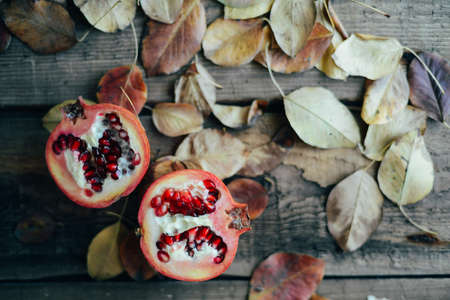 Ripe pomegranate fruit on wooden vintage background. Red juice pomegranate on dark background.  Fresh juicy pomegranate - whole and cut, top view.  Juicy pomegranates on woodの写真素材
