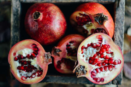 Ripe pomegranate fruit on wooden vintage background. Red juice pomegranate on dark background.  Fresh juicy pomegranate - whole and cut, top view.  Juicy pomegranates on woodの写真素材