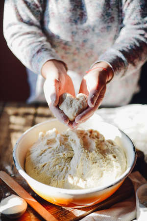 Close up view of baker kneading dough. Homemade bread. Hands preparing bread dough on wooden table. Preparing traditional homemade bread. Woman hands kneading fresh dough for making breadの写真素材
