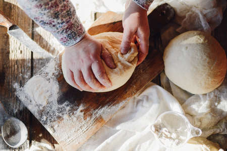 Close up view of baker kneading dough. Homemade bread. Hands preparing bread dough on wooden table. Preparing traditional homemade bread. Woman hands kneading fresh dough for making breadの写真素材