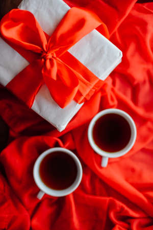 Valentine's Day concept. Gift with red bow  on the wooden background, Valentines. Valentines gift boxes tied with a red satin ribbon bow on  background. gift onの写真素材