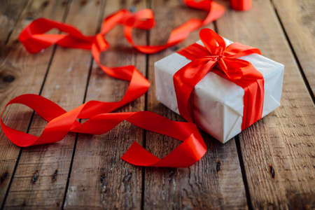 Valentine's Day concept. Gift with red bow  on the wooden background, Valentines. Valentines gift boxes tied with a red satin ribbon bow on  background. gift on , wedding dayの写真素材