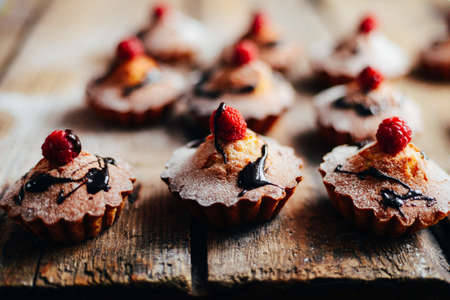 Delicious chocolate cupcakes with berries on wodeen table, top view. Homemade Chocolate Cupcake with chocolate frosting against a background. colorful cupcakesの写真素材