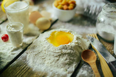 Ingredients for baking croissants - flour, wooden spoon, rolling pin, eggs, egg yolks, butter served on wooden background.の写真素材