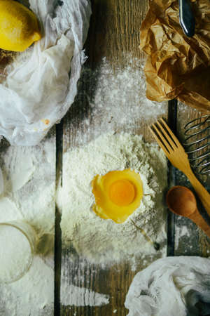 Ingredients for baking croissants - flour, wooden spoon, rolling pin, eggs, egg yolks, butter served on wooden background.の写真素材