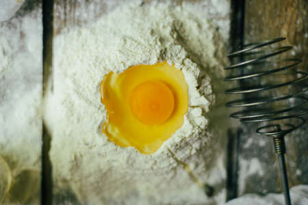 Ingredients for baking croissants - flour, wooden spoon, rolling pin, eggs, egg yolks, butter served on wooden background.の写真素材
