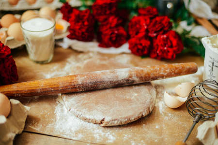 hands cut cookie from raw dough on a wooden table. Healthy baking ingredients - flour,  butter,...