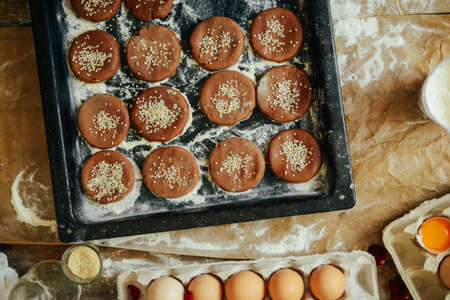 hands cut cookie from raw dough on a wooden table. Healthy baking ingredients - flour,  butter,...