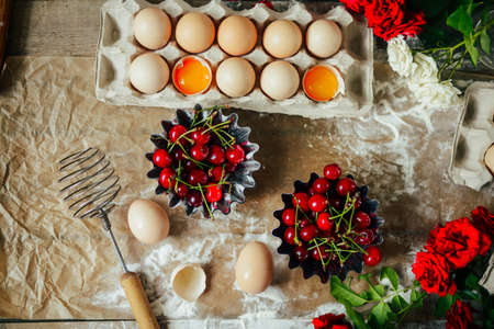 hands cut cookie from raw dough on a wooden table. Healthy baking ingredients - flour,  butter,...