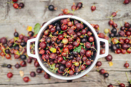 Fresh gooseberries in bowl on wooden background. Top view.の写真素材