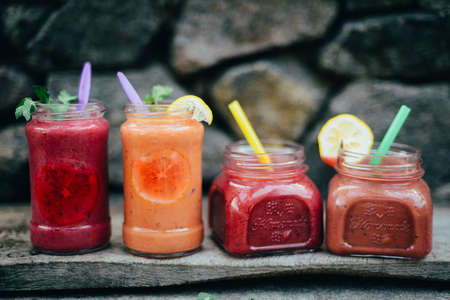 Assorted fruit shakes on white table. Smoothie concept. Selection of colorful smoothies on rustic wood background. Freshly blended fruit smoothies of various colorsの写真素材