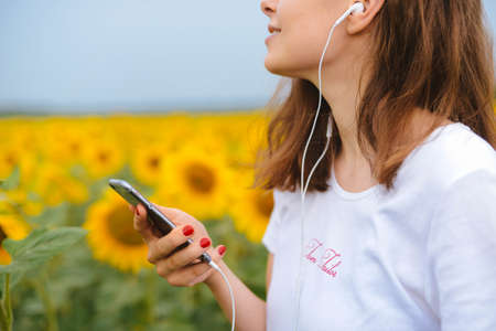 young beautiful girl  listen the music in your smartphone, outdoor portrait. Teenager listening to music. Woman listening music on her headphonesの写真素材