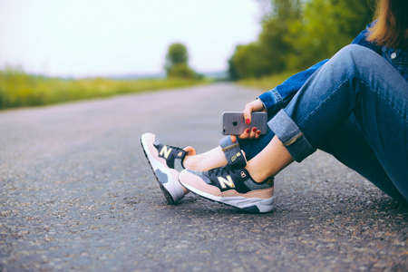 UKRAINE, KYIV - JULY 28, 2017:Young handsome girl wearing a fashionable outfit in the city. Female feet in jeans and sports shoes. Woman with pink and black New Balance shoesのeditorial素材
