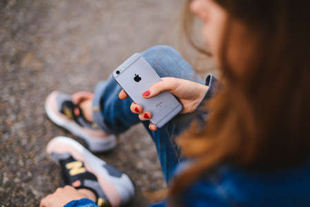 UKRAINE, KYIV - JULY 28, 2017:hipster female holding smart phone similar to iphone6s outdoor lifestyle. Close up of women's hands holding cell telephone. new modern people lifestyleのeditorial素材