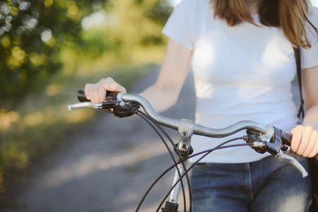 Beautiful young woman riding pink bicycle in green park. Girl on a bicycle in the sunset.の写真素材