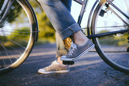 Legs of a woman in sneakers with a bicycle close upの写真素材
