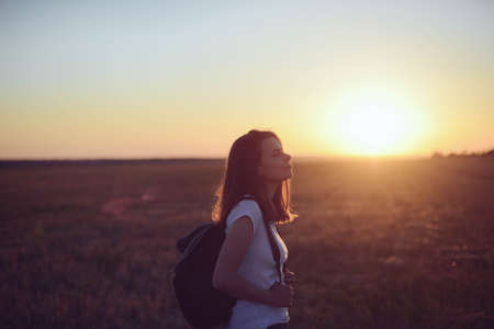 Portrait of happy and enjoying young woman on a meadow on a sunset. Cheerful girl on sunset. Lifestyle and happiness concept.の写真素材