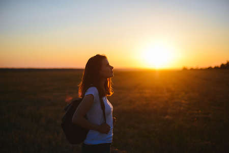 Portrait of happy and enjoying young woman on a meadow on a sunset. Cheerful girl on sunset. Lifestyle and happiness concept.の写真素材