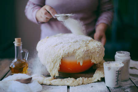 Close up view of baker kneading dough. Homemade bread. Hands preparing bread dough on wooden table....