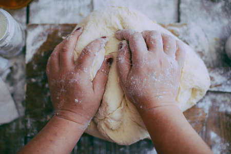 Close up view of baker kneading dough. Homemade bread. Hands preparing bread dough on wooden table. Preparing traditional homemade bread. Woman hands kneading fresh dough for making breadの写真素材