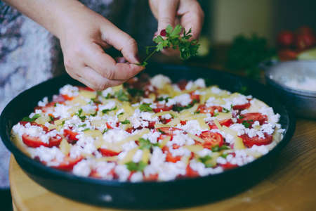 Raw pizza dough with sauce and ingredients on wooden table.の写真素材