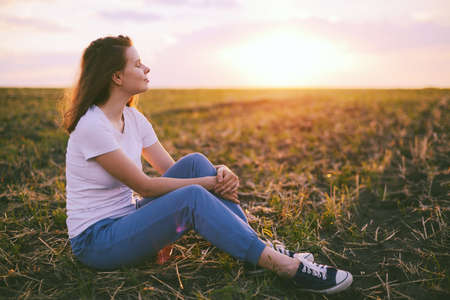 Young woman relaxing in summer sunset sky outdoor. People freedom style.の写真素材