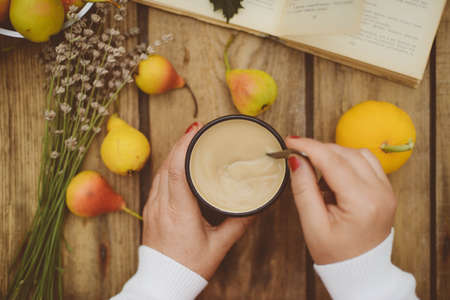 season, drink and morning concept - close up of tea cup on wooden table with autumn leaves and pearの写真素材