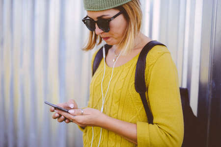 pretty hipster girl in the summer city with smartphone