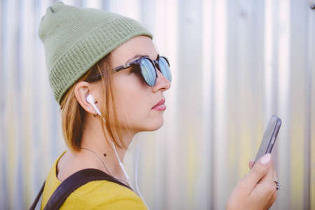 pretty hipster girl in the summer city with smartphoneの写真素材