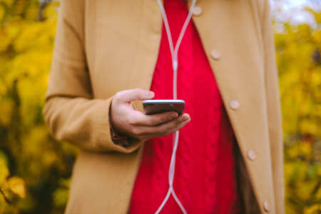 Hipster girl texting message on smartphone mobile in autumn natureの写真素材