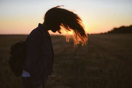 Portrait of happy and enjoying young woman on a meadow on a sunset. Cheerful girl on sunset. Lifestyle and happiness concept.の写真素材