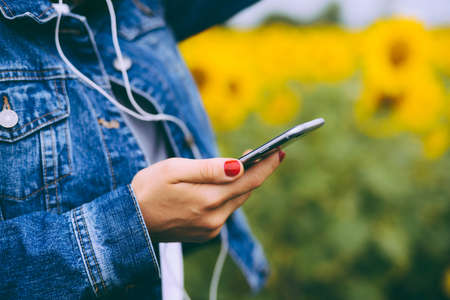 hipster female holding smart phone similar to iphone6s outdoor lifestyle. Close up of women's hands holding cell telephone. new modern people lifestyleのeditorial素材