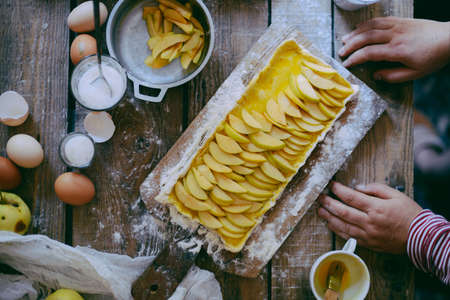 Woman cooking apple pie. Woman cooking apple pie. Traditional dessert for Independence Day. Dark food photo. Rustic style.の写真素材