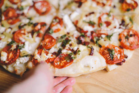  Margherita pizza with utensils and vegetable on slate plate.  Fresh pizza with tomatoes and basil on table closeup. の写真素材
