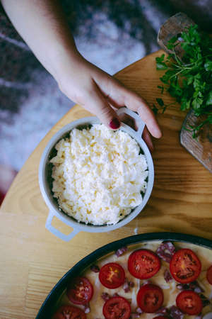 Raw pizza with sauce and ingredients on wooden table. Fresh o raw pizza, preparation in traditional...