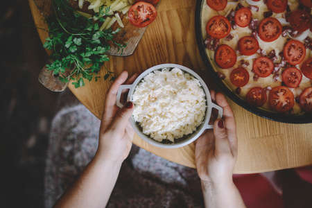 Raw pizza with sauce and ingredients on wooden table. Fresh o raw pizza, preparation in traditional style. Margherita pizza with utensils and vegetable on slate plateの写真素材