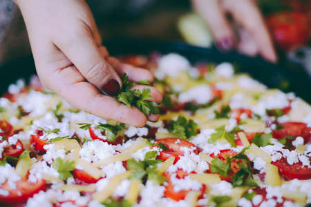 Raw pizza dough with sauce and ingredients on wooden table. Fresh o raw pizza, preparation in traditional style. Margherita pizza with utensils and vegetable on slate plateの写真素材