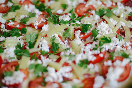 Raw pizza with sauce and ingredients on wooden table. Fresh o raw pizza, preparation in traditional style. Margherita pizza with utensils and vegetable on slate plateの写真素材