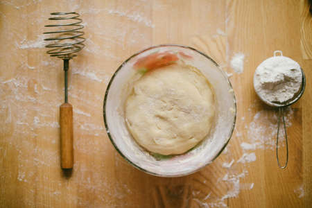 Ingredients for baking - flour, wooden spoon, rolling pin, eggs. Homemade tart pie preparation, dough with yeast and rolling pin on  rustic kitchen tableの写真素材