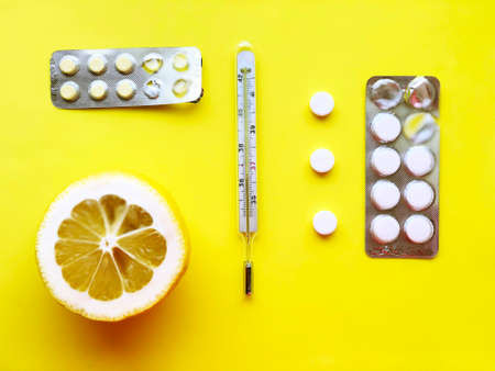 Pills, thermometer on a yellow background, top view. の写真素材