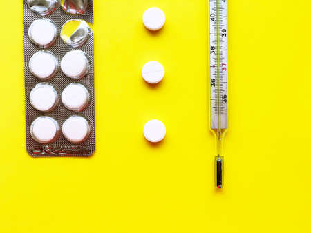 Pills, thermometer on a yellow background, top view. の写真素材