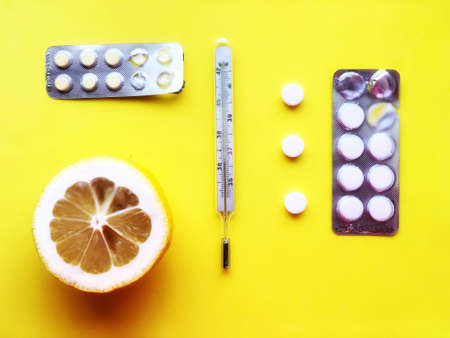 Pills, thermometer on a yellow background, top view. の写真素材