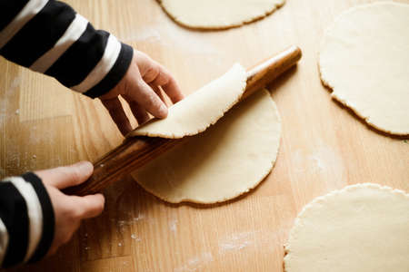 A woman  rolling dough for pie in kitchenの写真素材