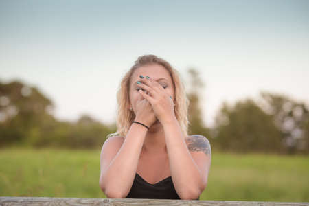 Blonde woman covering face with hands. Concept - embarrassed, laughing or surprisedの写真素材